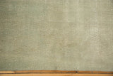 Secured end of a distressed pale dusty sea foam green Oushak rug, showing light foundation.