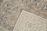 Folded corner of Sparta carpet, showing distressed muted floral pile and beige hand-knotted foundation.