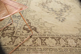 Corner detail of distressed Oushak carpet, highlighting geometric arabesques in ivory and charcoal.