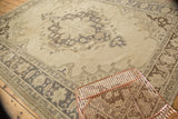 Distressed Oushak rug corner showing geometric arabesques and time-softened brown tones.