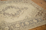 Distressed Oushak rug corner, ivory field, charcoal geometric arabesques, floral border.