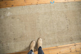Distressed vintage Oushak runner with faint medallions and abrashed sand, ivory, coffee tones.