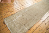 Distressed Oushak runner showcasing abrashed antique ivory and sand, with faint medallion shapes.