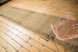 Faded beige and brown primitive geometric gul motif on a distressed Oushak runner.