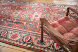 Mahalati carpet's meandering vine border and field's scrolling floral palmettes, cherry red and navy.