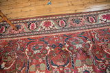 Mahalati carpet detail: cherry red field, navy border, scrolling tendrils, and palmettes.