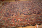Corner view of antique Mahal carpet, featuring dense herati motif field and madder red border.
