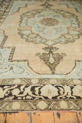 Distressed Oushak rug corner, soft scalloped contour, visible foundation, peach, blue, brown.