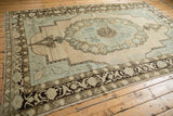 Distressed Oushak rug with faded floral border in chocolate brown and soft blue field.