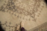 Distressed vintage Oushak rug detail: ivory field, brown scalloped medallion, germinating plants.