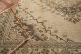 Vintage distressed Oushak carpet close-up with ivory field, chocolate brown germinating plant motifs.