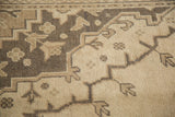 Distressed Oushak rug pile: intricate brown geometric, plant motifs on an ivory ground.