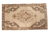 Distressed Vintage Oushak rug with a stylized central medallion in antique ivory and brown tones.