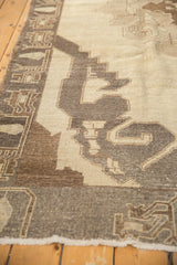 Textural close-up of the distressed Oushak rug's stylized brown and ivory geometric pattern.