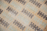 Secured end of distressed Oushak rug, showing saffron, seafoam, and chocolate geometric patterns.