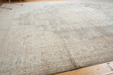 Distressed vintage Sparta carpet showcasing muted slate grey and antique ivory curvilinear patterns.