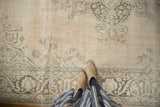 Close-up of distressed vintage Sivas carpet, showing faded charcoal florals and patterned border.
