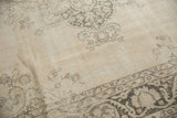 Distressed texture of the vintage Sivas carpet with faded floral motifs in ivory and charcoal.