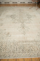 Distressed vintage Sivas carpet shows worn ivory field with faded charcoal floral patterns and ornate border.