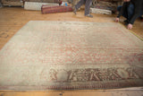 Corner view of distressed Anatolian carpet with faded raspberry herati pattern and dark coffee brown border.