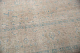 Distressed Kashan carpet pile with faint scrolling blue vinery on dusty mauve apricot.