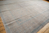Distressed vintage Kashan carpet showing faded blue patterns and exposed foundation near the edge.