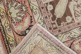Distressed vintage Turkish Kaisary carpet's folded corner, showing worn terracotta, beige floral pile and woven reverse.