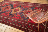 Geometric stepped medallions and red floral field on a vintage Belouch carpet.