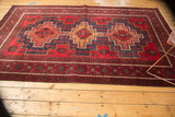 Geometric medallion detail of Persian Belouch carpet in cherry red, navy blue, and low pile.