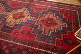 Detail of cherry red and navy Belouch geometric carpet with visible pile etching.
