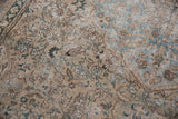 Distressed traditional Tabriz carpet showing worn dusty teal and ivory floral pattern.