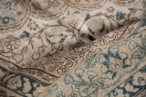Distressed vintage Tabriz carpet texture with faded ivory and dusty teal motifs.