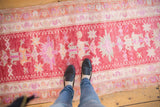 Distressed Oushak runner with low pile, softened pink, orange, ivory geometric patterns.