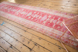 Soft pink and violet geometric and curvilinear patterns on a distressed Oushak runner.