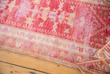 Distressed Oushak runner's curvilinear border and geometric main field in pink, violet, and beige.