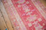Distressed pink Oushak runner with geometric pinwheel motifs and ivory curvilinear border.