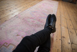 Vintage distressed Oushak runner, its low pile showing faded pink, ivory, and blue tones.
