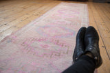 Distressed vintage Oushak runner, its low pile showcasing faded pink and blue gul motifs.