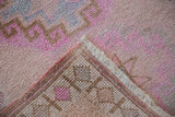 Distressed Oushak runner: low pile, visible knot heads, pink geometric pattern, intact selvage.