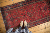 Vintage Belouch runner, geometric Herati motif in brick red and navy, with low pile and visible knot heads.