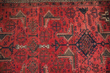 Vintage Belouch runner's geometric Herati-inspired motifs in navy and charcoal on brick red low pile.