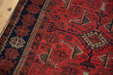 Geometric Herati-inspired motifs in brick red, navy, and ivory on vintage Belouch runner.