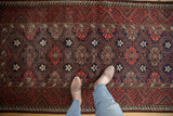 Vintage Belouch runner displaying repeating geometric floral motifs in deep reds, navy, and ivory.