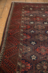 Red geometric border and dark navy, ivory floral field patterns on a vintage Belouch runner.