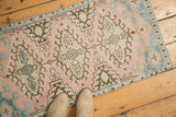 Distressed Oushak rug's worn texture displaying blush, sky blue, and brown motifs.