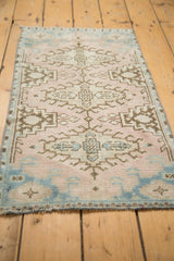 Distressed Oushak rug corner, low pile dusty rose and sky blue geometric motifs, plus fringe.