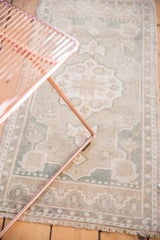 Scalloped ivory and pale slate blue medallion detail with fringe on a distressed Oushak rug.