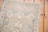 Distressed Oushak rug's scalloped medallion with soft ivory, silver, and slate blue motifs.