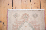 Distressed Oushak rug with ivory fringe, intact faded burgundy side selvage, and muted patterns.