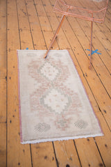 Faded burgundy and silver geometric pattern on distressed Oushak rug's lower corner.